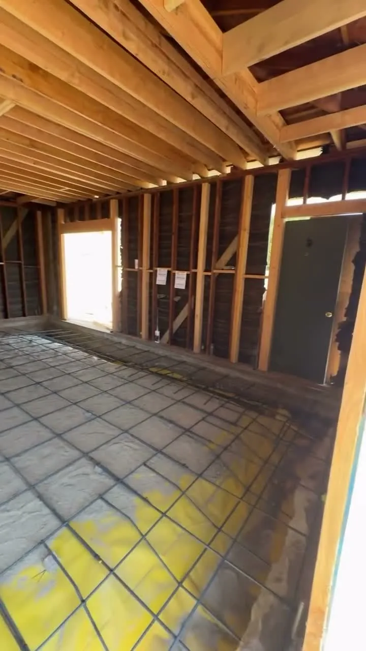 Garage conversion ADU under construction — rebar over the vapor barrier inside the stripped garage shell, Brea, Avorino