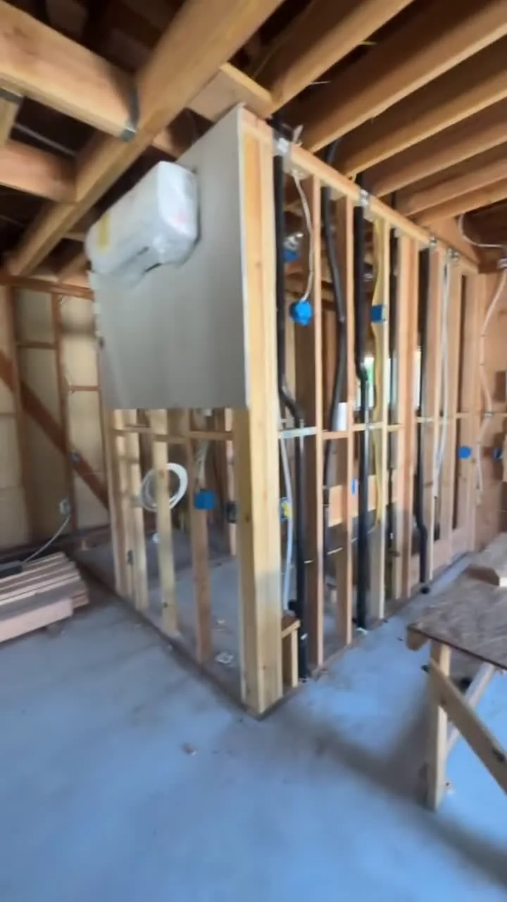 Garage conversion ADU under construction — bathroom partition framing with drain and supply rough-ins, Brea, Avorino