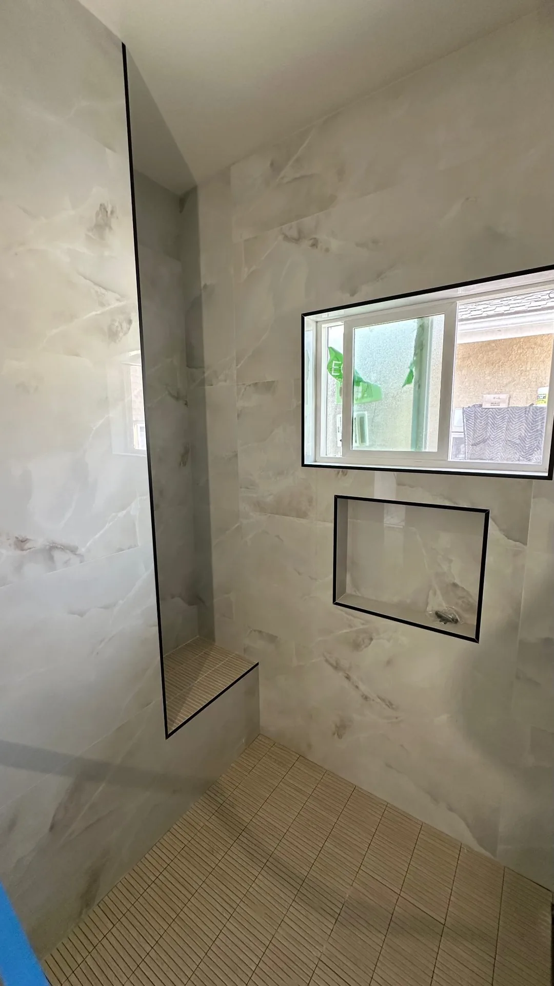 Garage conversion ADU under construction — shower tile set before grout, black-trim niche, Brea, Avorino