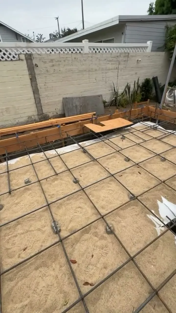 Attached ADU under construction — slab rebar over the sand pad inside the forms, Orange, Avorino